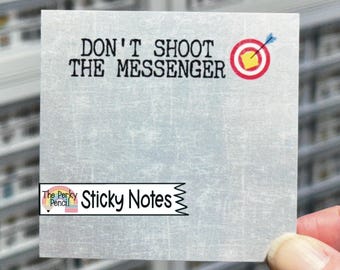 May include: A square sticky note with a light grey distressed texture background. The text DON'T SHOOT THE MESSENGER is printed in black at the top, next to a red and white target graphic with a blue arrow. A logo reads The Perky Pencil Sticky Notes.