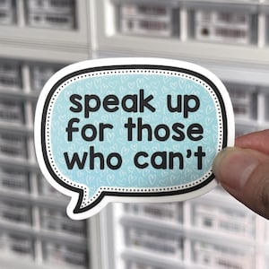 May include: A speech bubble sticker with a light blue background featuring a repeating white heart pattern. The sticker has a thick black border with a white dotted inner line and black text that reads: speak up for those who can't.