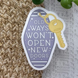 Pu&ograve; includere: Un adesivo a forma di portachiavi da motel color lavanda con una chiave gialla attaccata in alto. L'adesivo mostra il testo bianco OLD WAYS WON'T OPEN NEW DOORS, accentuato da piccole stelle a quattro punte all'interno del bordo viola.