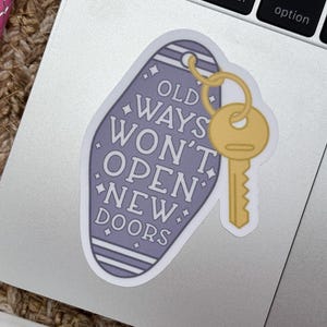 Pu&ograve; includere: Un adesivo a forma di portachiavi da motel vintage di colore viola tenue con testo bianco che recita OLD WAYS WON'T OPEN NEW DOORS. L'adesivo presenta una chiave color oro attaccata nell'angolo in alto a destra e piccoli accenti a stella.