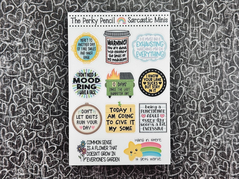 May include: A sheet of colorful stickers with sarcastic sayings. The stickers are round, square, and rectangular. Some of the sayings include "I don't need a mood ring, I have a face", "Here's to another day of fake smiles and inner rage", and "Today I am going to give it my some".