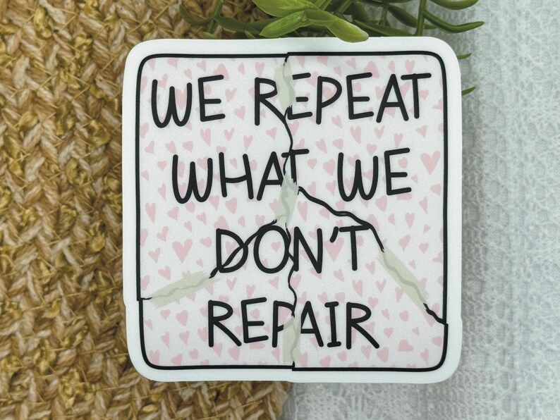 May include: White sticker with a cracked design. The sticker has a pink background with small pink hearts. The text on the sticker reads "We repeat what we don't repair."