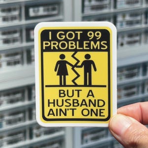 May include: Yellow warning sign with black text and icons. The sign reads "I got 99 problems but a husband ain't one". The icons depict a couple breaking up.