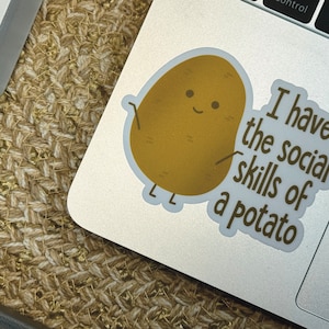 May include: A sticker with a cartoon potato with a smiling face and the text "I have the social skills of a potato".
