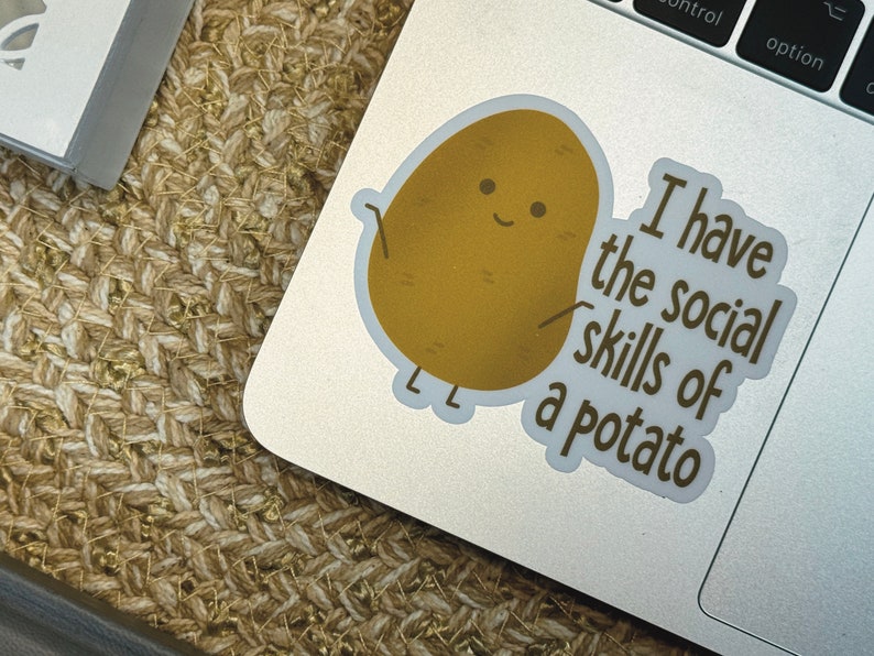 May include: A sticker with a cartoon potato with a smiling face and the text "I have the social skills of a potato".