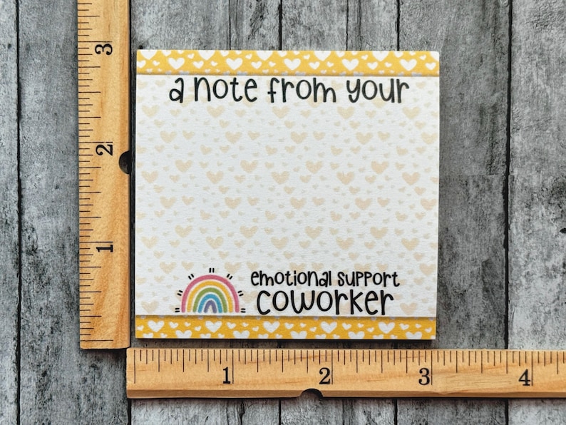 K&ouml;nnte beinhalten: Ein gelber und wei&szlig;er Notizblock mit einem Regenbogen und dem Text "a note from your emotional support coworker".