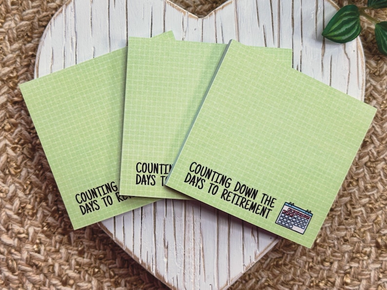 K&ouml;nnte beinhalten: Drei quadratische hellgr&uuml;ne Haftnotizen mit wei&szlig;em Gittermuster. Jede Notiz zeigt den schwarz gedruckten Text "COUNTING DOWN THE DAYS TO RETIREMENT" und eine kleine Grafik eines Kalenders mit blauem Kopf und roten Markierungen auf den Daten.