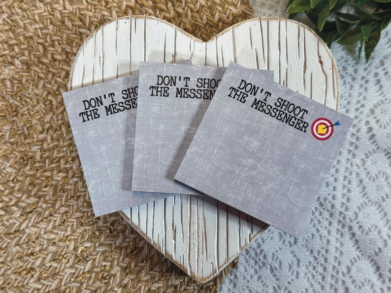 May include: Three gray sticky notes with the text "Don't Shoot The Messenger" on each. The third note has a red and yellow target with an arrow in the center.