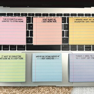 May include: A laptop keyboard with six colourful sticky notes. The notes have humorous phrases like "This is exactly why I wanted to stay home" and "Don't blame me I just work here."