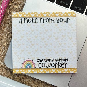 K&ouml;nnte beinhalten: Ein gelber Haftnotiz mit wei&szlig;em Hintergrund und einem Regenbogen-Design. Der Notiz steht "a note from your emotional support coworker".