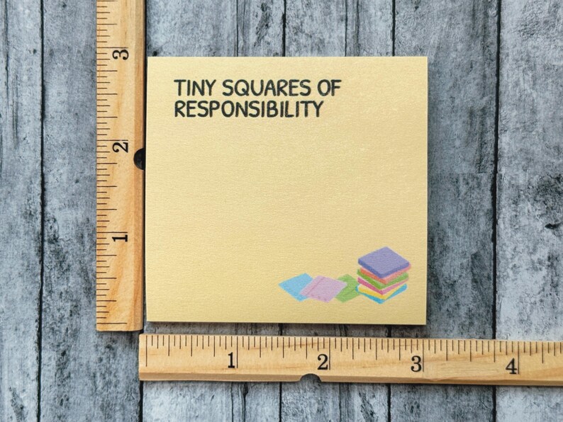 Peut inclure: Un bloc-notes carr&eacute; jaune clair avec le texte "TINY SQUARES OF RESPONSIBILITY" en noir. Une pile de carr&eacute;s color&eacute;s se trouve dans le coin inf&eacute;rieur droit. Une r&egrave;gle en bois est sur le c&ocirc;t&eacute; gauche et en bas.