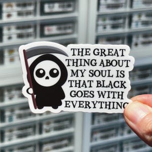 May include: A white sticker with a black cartoon Grim Reaper holding a scythe. The text on the sticker reads "The great thing about my soul is that black goes with everything."
