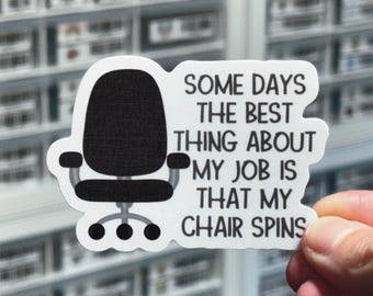 以下が含まれることがあります： 黒いオフィスチェアと「Some days the best thing about my job is that my chair spins.」というテキストが書かれた白いステッカー