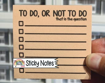 以下が含まれることがあります： 上部に黒字で「TO DO, OR NOT TO DO that is the question」と印刷された、正方形の薄茶色の付箋。テキストの下には、左側に空の四角いチェックボックスが付いた6本の水平線が引かれています。