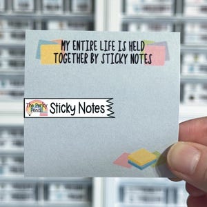 May include: A square light blue sticky note featuring the black text MY ENTIRE LIFE IS HELD TOGETHER BY STICKY NOTES at the top. A white banner with the text The Perky Pencil Sticky Notes is centered, and a small stack of colorful notes is at the bottom.
