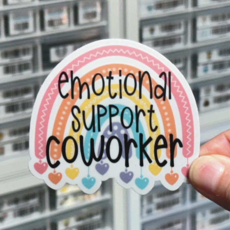 Puede incluir: Una pegatina troquelada con un dise&ntilde;o de arco&iacute;ris en tonos pastel y el texto negro "emotional SUPPORT COWORKER" impreso en el centro. El arco&iacute;ris est&aacute; decorado con peque&ntilde;as formas de coraz&oacute;n colgantes en colores rosa, naranja, amarillo, azul y morado.