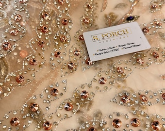 May include: Beige tulle fabric with a delicate floral pattern embellished with clear and rose gold rhinestones. The fabric is shown with a business card that reads "S. Porch Clothing - Fabrics | Outfits | Bespoke Service - Ready to Wear (RTW) | Personal Stylist"