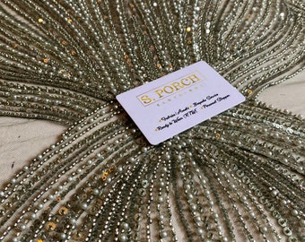 May include: Close-up of a fabric with silver and gold sequins and pearl beads. The fabric is arranged in a fan shape. A business card for S. Porch Clothing is visible in the bottom right corner. The card reads "Fabric Finds - Bespoke Service - Ready to Wear (RTW) - Personal Shopper."