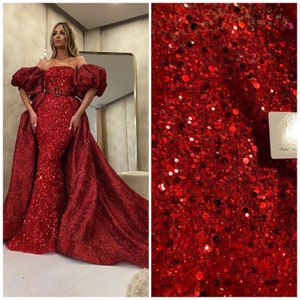 Puede incluir: Una tela roja de lentejuelas con una textura brillante y reluciente. La tela es perfecta para crear prendas glamorosas como vestidos de noche o vestidos.