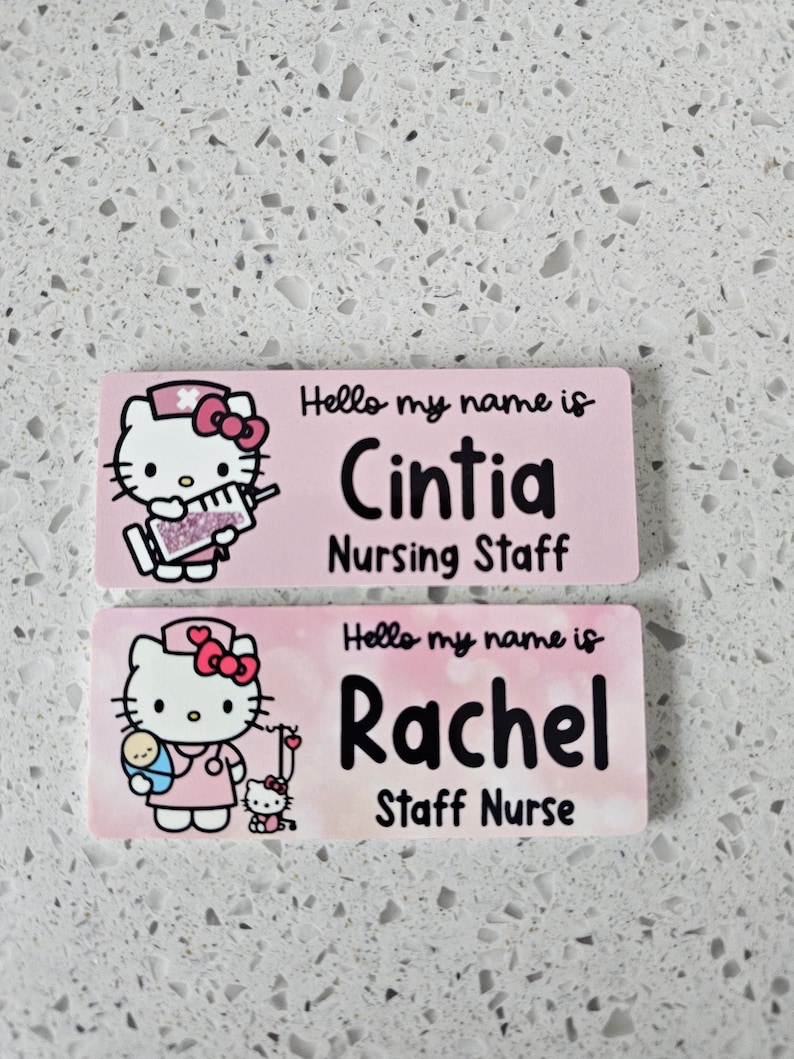 May include: Two rectangular name badges with a light pink background. The top badge features Hello Kitty holding a syringe and the text Hello my name is Cintia Nursing Staff. The bottom badge shows Hello Kitty with a baby and the text Hello my name is Rachel Staff Nurse.