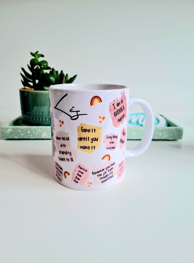 Puede incluir: Taza de cer&aacute;mica blanca con un dise&ntilde;o rosa y amarillo. La taza tiene un asa y presenta citas inspiradoras y el texto "I am a BADASS nurse".