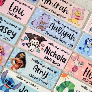 May include: A collection of rectangular name badges featuring the text Hello my name is followed by various names and job titles. Each badge displays colorful cartoon characters including Winnie the Pooh, Stitch, Moana, and Piglet on pastel backgrounds.