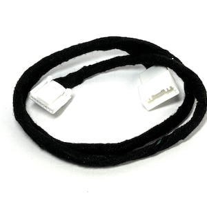 May include: A black wire with two white connectors on each end. The wire is covered in black fabric.