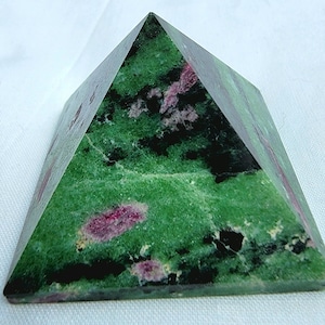 May include: A green and pink pyramid-shaped crystal. The crystal has a smooth, polished surface and is made of a natural stone.