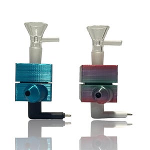 May include: Two glass and 3D-printed smoking accessories. One is teal and black, the other is red, green, and purple with a white and black component. Both have a clear glass bowl and a cylindrical, angled base.