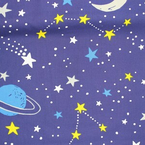 Könnte beinhalten: Dunkelblauer Stoff mit Weltraum-Muster. Das Design zeigt weiße Sterne, gelbe Sternbilder, einen blauen Planeten mit Ringen, einen weißen Mond und eine Sternschnuppe. Kleine weiße Punkte sind über den Stoff verteilt.