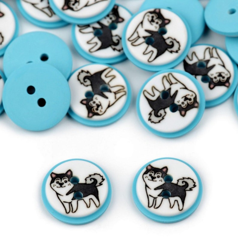 May include: A collection of blue and white round buttons with a black and white illustration of two dogs on each button.