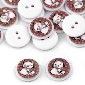 May include: A collection of white round buttons with a two-hole design. Some buttons feature a pink and brown design with a white cat illustration.