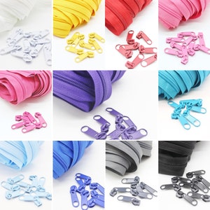 Könnte beinhalten: Sortiment an Reißverschluss-Zippern in verschiedenen Farben, darunter Weiß, Gelb, Rot, Rosa, Lila, Blau, Hellblau, Grau und Schwarz. Die Reißverschluss-Zipper sind aus Kunststoff und haben einen Metall-Schieber. Die Reißverschluss-Zipper sind in einem Rastermuster auf weißem Hintergrund angeordnet.