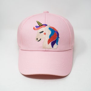 Könnte beinhalten: Eine rosafarbene Baseballkappe mit einem gestickten Einhorn-Motiv. Das Einhorn hat ein gelbes Horn, eine blaue und rote Mähne und einen lila und blauen Schwanz.