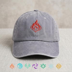 May include: A gray baseball cap with a red flame logo embroidered on the front. The cap has a curved brim and an adjustable strap. The design is a stylized flame, and the cap is made of a soft, washed fabric.