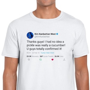 May include: A white t-shirt with a blue Twitter post on the front. The post is from Kim Kardashian West and reads "Thanks guys! I had no idea a pickle was really a cucumber! U guys totally confirmed it!" The post has 23.3K retweets, 267 quote tweets, and 26.9K likes.