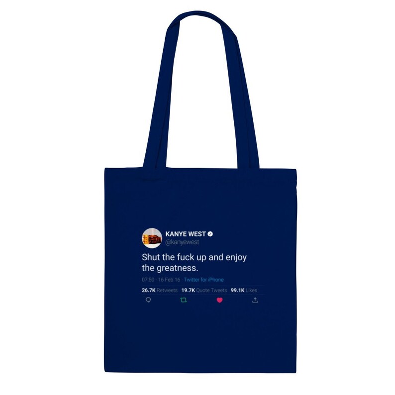 May include: A navy blue tote bag with a white Twitter post on it. The post is from Kanye West and reads "Shut the fuck up and enjoy the greatness." The post has 26.7K retweets, 19.7K quote tweets, and 99.1K likes.