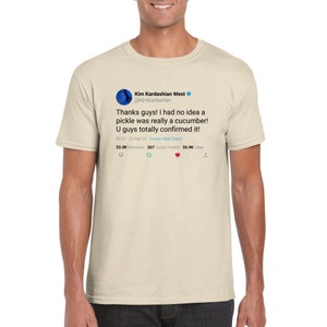 May include: A beige t-shirt with a printed image of a tweet from Kim Kardashian West. The tweet reads: "Thanks guys! I had no idea a pickle was really a cucumber! U guys totally confirmed it!" The tweet was posted on February 10, 2010, and has 23.3K retweets, 267 quote tweets, and 26.9K likes.
