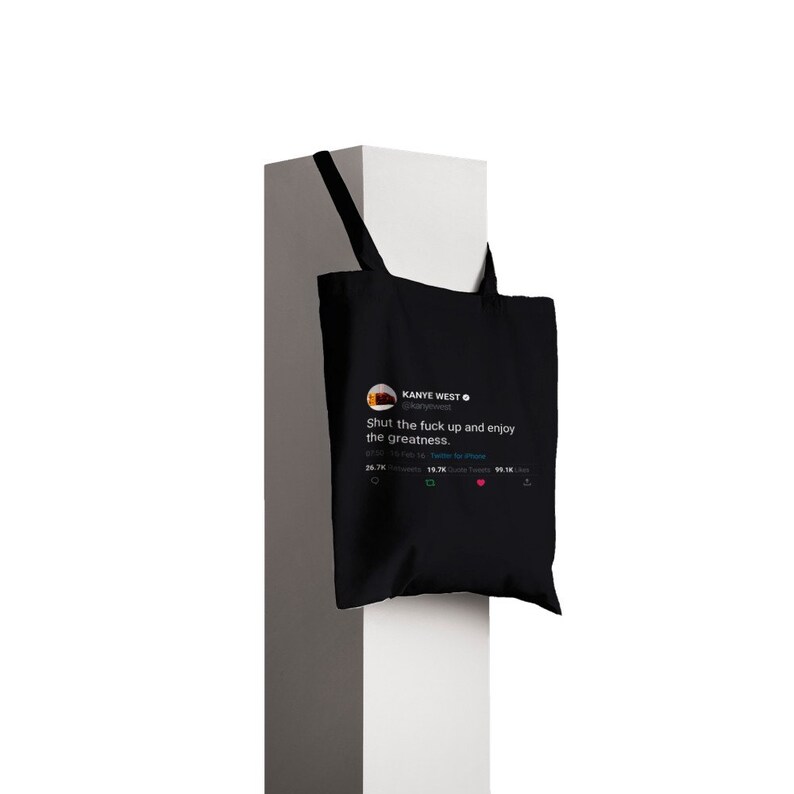 May include: Black tote bag with a white graphic of a tweet from Kanye West that reads "Shut the fuck up and enjoy the greatness."