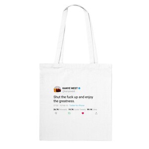 May include: White tote bag with a printed image of a tweet from Kanye West. The tweet reads "Shut the fuck up and enjoy the greatness." The tweet has 26.7K retweets, 19.7K quote tweets, and 99.1K likes.