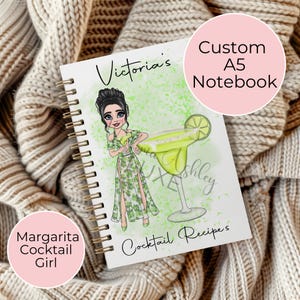 May include: A white A5 notebook with a green and white illustration of a woman holding a margarita glass. The text "Victoria's Cocktail Recipes" is on the cover.