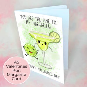 Puede incluir: Una tarjeta de San Valent&iacute;n con un dise&ntilde;o de dibujos animados de un vaso de margarita y una lima. La tarjeta dice "YOU ARE THE LIME TO MY MARGARITA!" y "HAPPY VALENTINES DAY". Un c&iacute;rculo rosa en la parte inferior izquierda dice "A5 Valentines Pun Margarita Card".