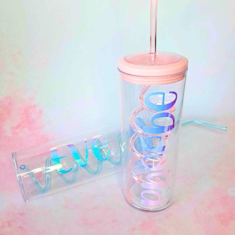 May include: Two clear plastic tumblers with reusable straws. The tumblers have iridescent vinyl lettering that reads "Chloe" and "Eve".