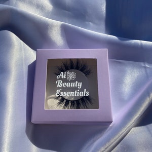 May include: A purple box with a clear window showing a pair of black false eyelashes. The box has the text "Ai Beauty Essentials" printed on it.