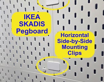 Op de afbeelding: Twee witte IKEA SKADIS pegboards die naast elkaar zijn bevestigd met horizontale montageclips. De pegboards hebben een uniform raster van verticale ovale sleuven. De witte kunststof clips zijn over de naad geplaatst.