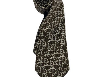 May include: A rolled brown tie with a repeating white pattern. The tie is made of a smooth fabric and is displayed against a white background. The pattern consists of the letters "D" and "R" intertwined.