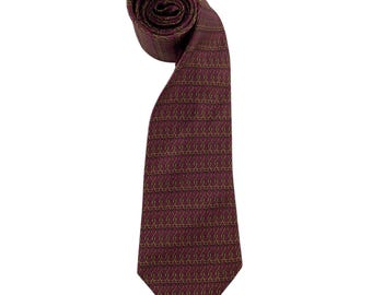 May include: A necktie in a deep burgundy color featuring a repeating pattern of small, interlocking gold-toned chain-link motifs. The tie is rolled at the top and tapers down to a pointed end, displaying a consistent geometric design throughout the fabric.