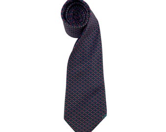 May include: A rolled-up navy blue tie with a repeating pattern of small red and green shapes. The tie is made of a smooth fabric and is displayed against a white background. The tie is a classic accessory for formal wear.