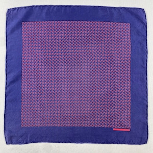 May include: A square pocket square in deep purple with a wide solid border. The central panel features a repeating geometric pattern of small, interconnected pink swirls. A small, rectangular pink label is stitched in the bottom right corner.