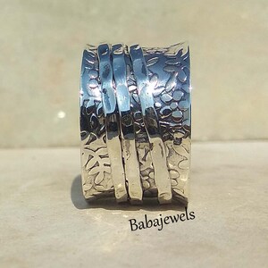 May include: Silver spinning ring with a floral design. The ring is made of multiple bands that spin around each other.